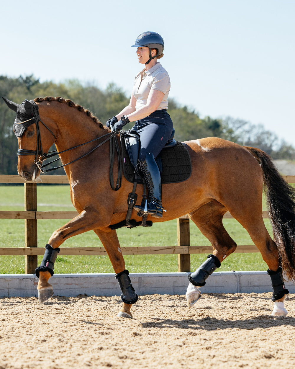 LeMieux 3D Mesh Self Cool Dressage Saddle Pad - Black, shown on a brown horse with person riding  in an outdoor setting with a wooden fence and green grass | Malvern Saddlery