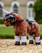 LeMieux Toy Pony - "Gracie", Plush toy horse with a bridle on a gravel surface with a blurred background | Malvern Saddlery