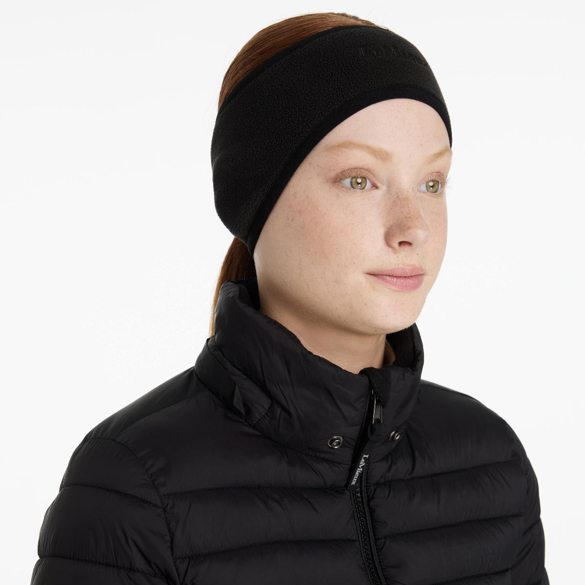 LeMieux Fleece Earwarmer Headband - Black; shown on woman wearing black puffer jacket | Malvern Saddlery