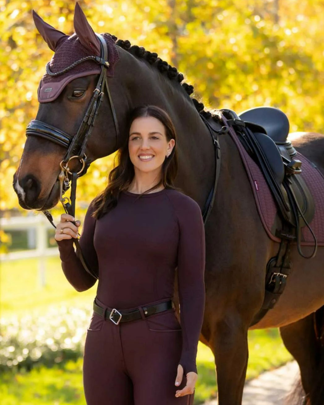 LeMieux Britney Seamless Long Sleeve Top - Damson [maroon] on woman next to horse | Ladies Activewear | Malvern Saddlery