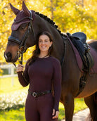 LeMieux Britney Seamless Long Sleeve Top - Damson [maroon] on woman next to horse | Ladies Activewear | Malvern Saddlery
