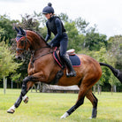 LeMieux Suede Close Contact Jumping Saddle Pad, Classic Ear Bonnet  on Person riding a brown horse in an outdoor setting with trees in the background