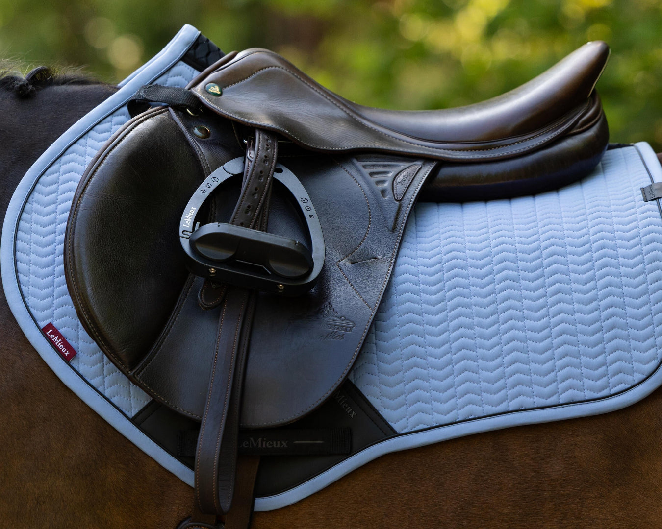 LeMieux Essence Close Contact Square Saddle Pad - Powder Blue; close up on chestnut horse with brown saddle outdoor background | Tack Shop | Malvern Saddlery