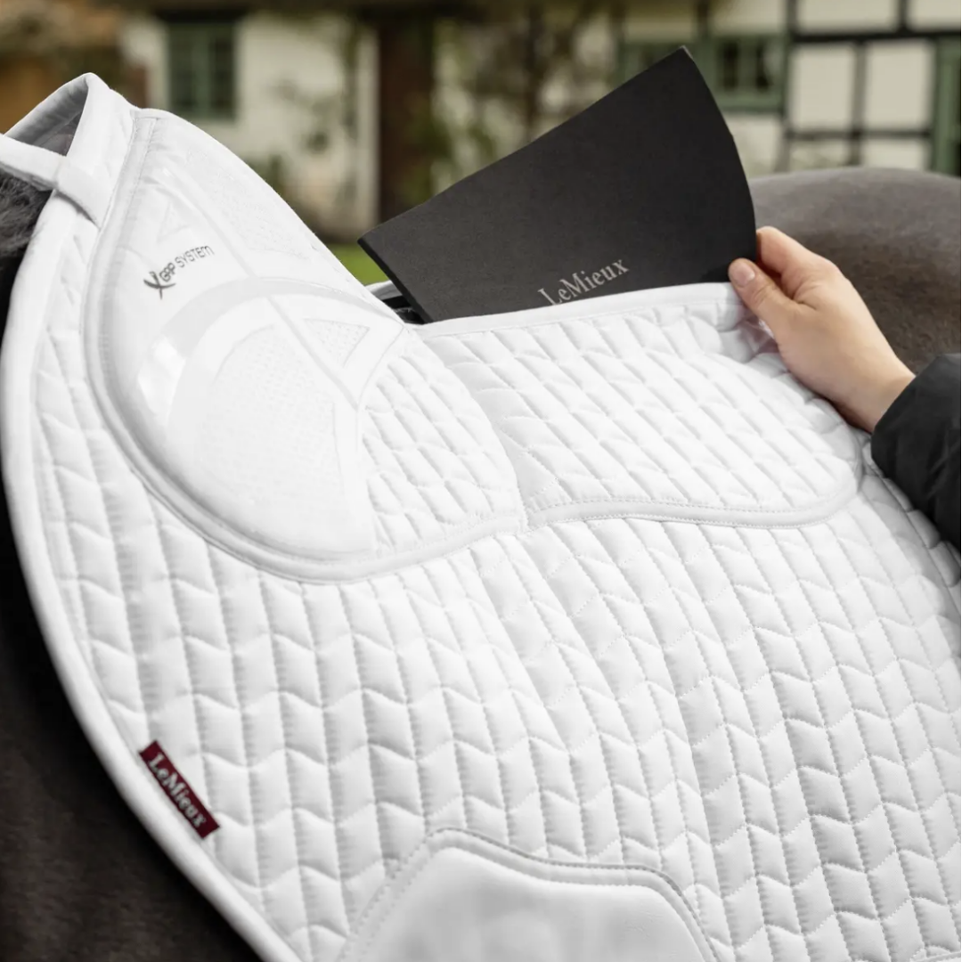 LeMieux ProSorb Plain 2 Pocket Close Contact Square Saddle Pad - White, on horse with person inserting pad into back pocket, outdoor background | Tack Shop | Malvern Saddlery