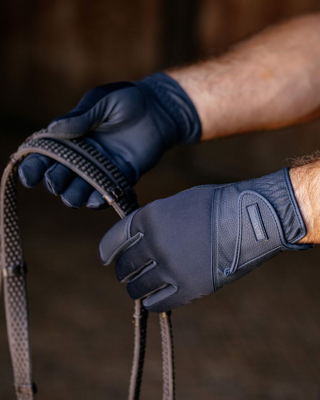 LeMieux Hybrid Riding Gloves - Navy, shown on man in barn holding reins | Malvern Saddlery