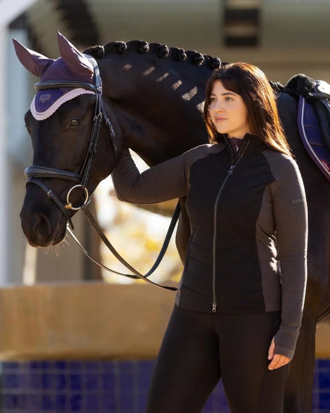 LeMieux Maddie Hybrid Jacket - Black, shown on woman standing next to horse | Ladies Outerwear | Malvern Saddlery