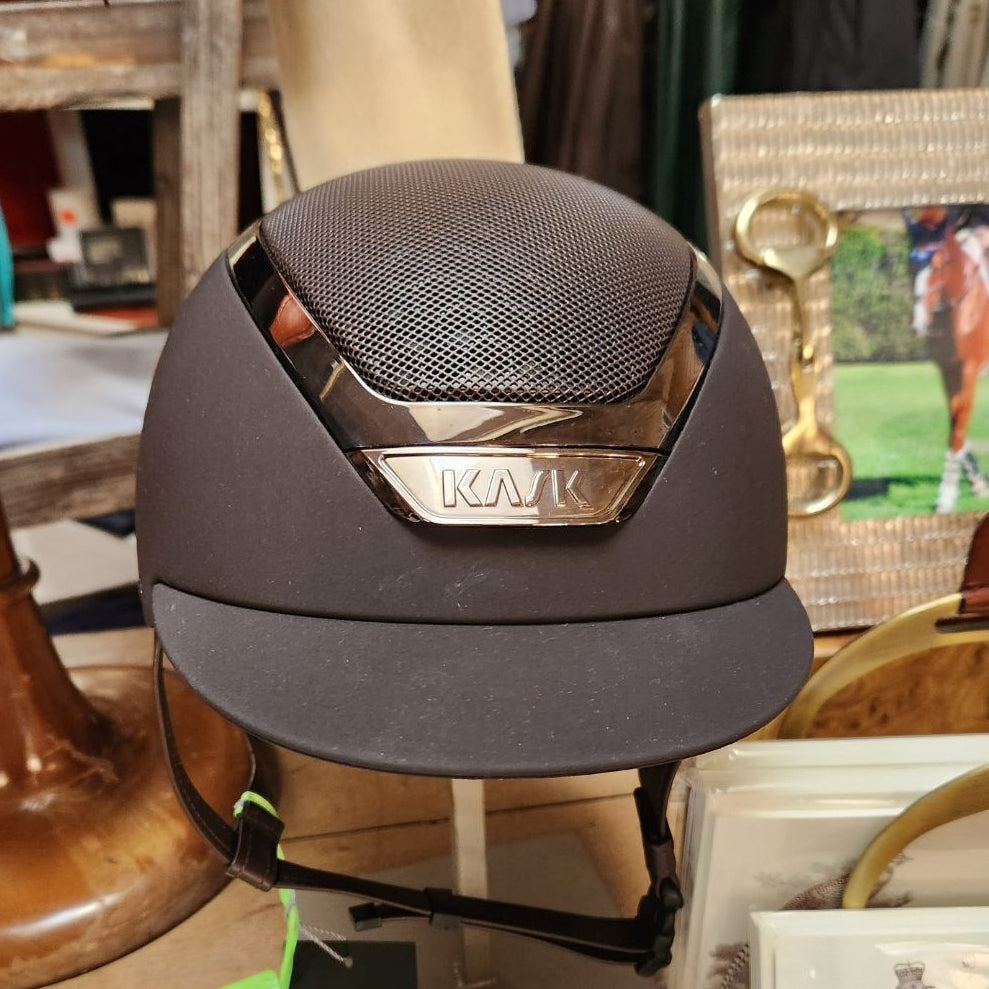 Brown equestrian helmet with 'Kask' branding on a mannequin head in a store setting.