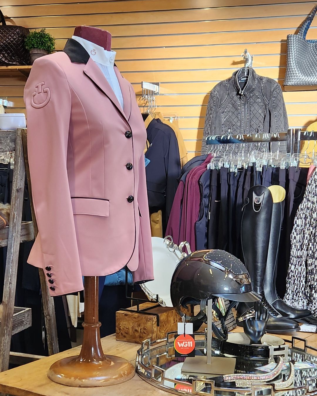 Pink blazer on a mannequin with a wooden base in a store setting.