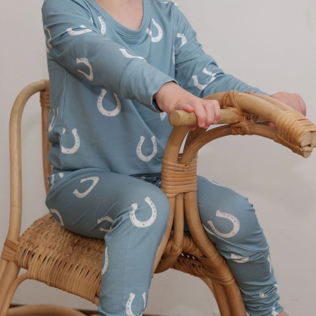 Kids Equestrian Horseshoe Pajamas - Blue; neck downshown on kid sitting on chair | Malvern Saddlery
