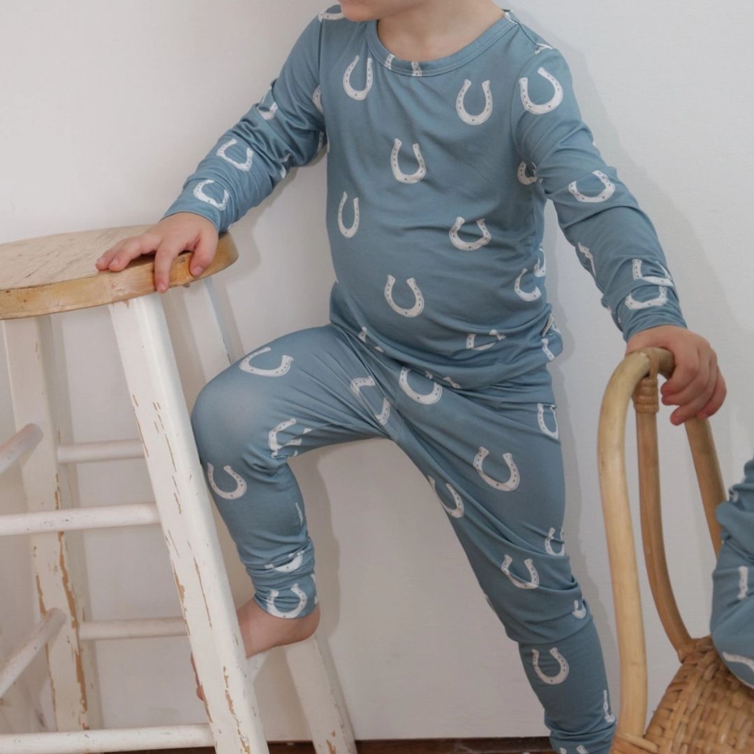 Kids Equestrian Horseshoe Pajamas - Blue; neck downshown on kid standing by stool | Malvern Saddlery