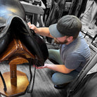 Person conditioning leather saddle [in-store]. Ovis & Castor Leather Balm | Tack Care | Boot Care | Malvern Saddlery