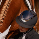 KASK Equestrian Star Lady Chrome Helmet - Navy with Silver frame, shown on rider sitting next to chestnut horse | Malvern Saddlery