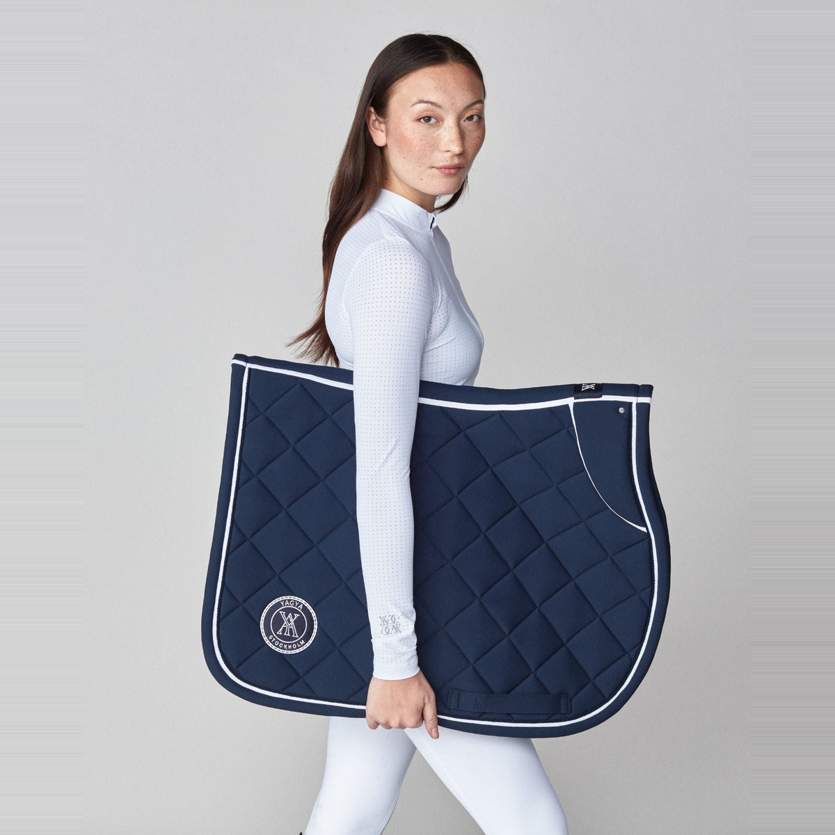 Yagya Performance Jump Saddle Pad - Navy, held by model | Malvern Saddlery